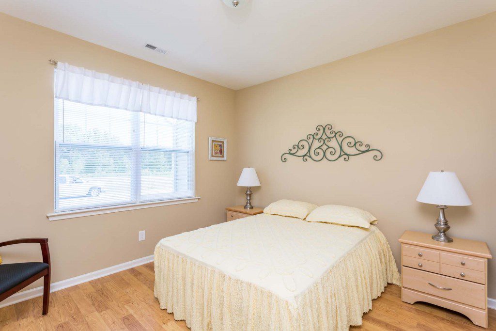 Comfortably furnished resident bedroom with a large window at Avendelle at Lazy River